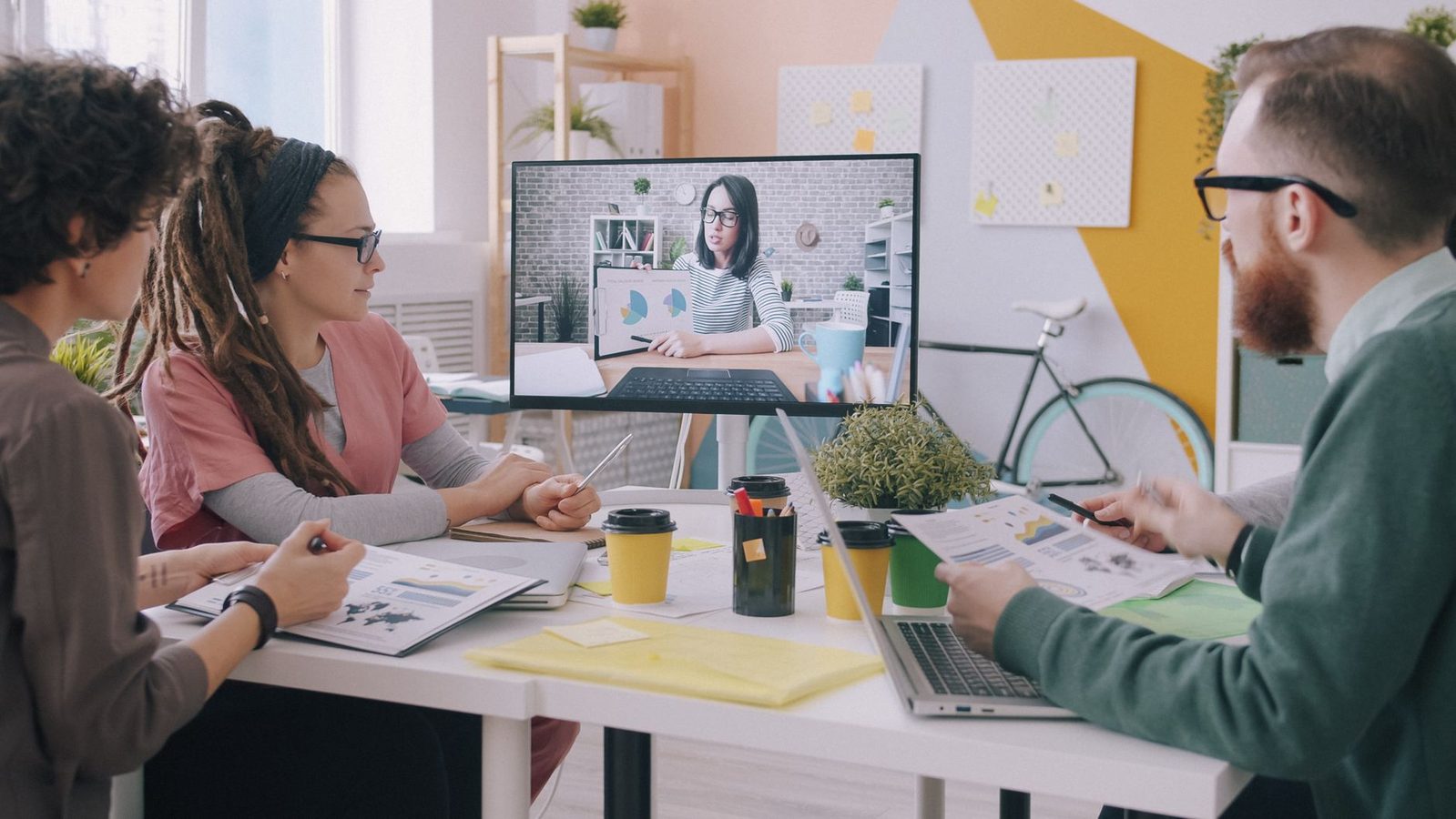 Colleagues on a video call in a bright office with laptops open on the table